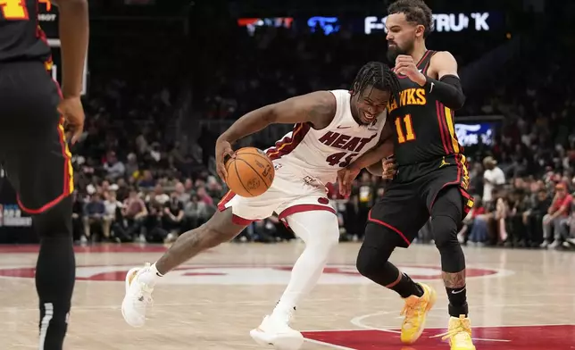 Miami Heat guard Davion Mitchell (45) dribbles against Atlanta Hawks forward Jalen Johnson (1) in overtime of an NBA play-in tournament basketball game against the Friday, April 18, 2025, in Atlanta. (AP Photo/Brynn Anderson)