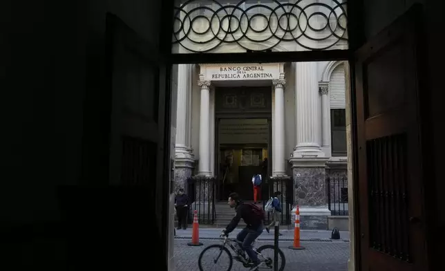 A cyclist rides past the Central Bank in Buenos Aires, Argentina, Monday, April 14, 2025. (AP Photo/Natacha Pisarenko)