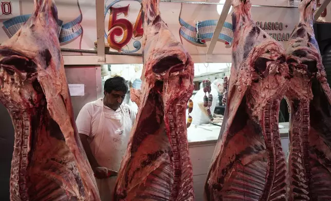 A worker cuts meat at a butcher shop in Buenos Aires, Argentina, Monday, April 14, 2025. (AP Photo/Natacha Pisarenko)