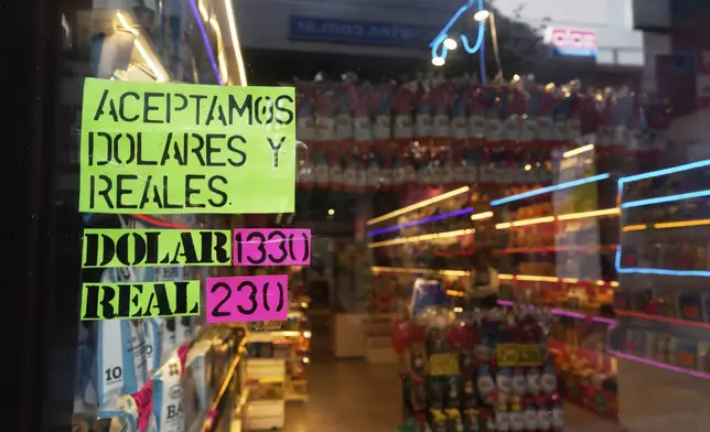 A sign displays the exchange rate between the U.S. dollar and the Argentine peso that is used at the store in Buenos Aires, Argentina, Monday, April 14, 2025. (AP Photo/Natacha Pisarenko)