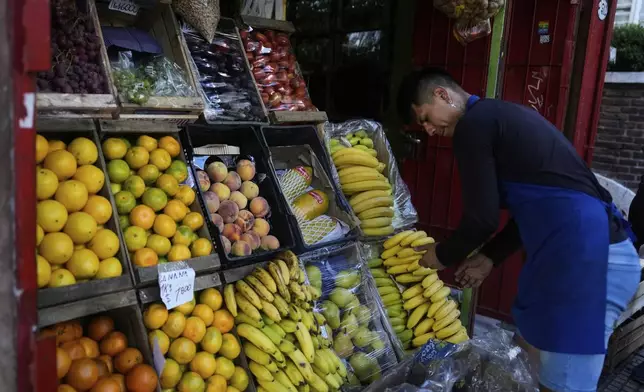 A produce vendor arranges bananas at his store in Buenos Aires, Argentina, Monday, April 14, 2025. (AP Photo/Natacha Pisarenko)