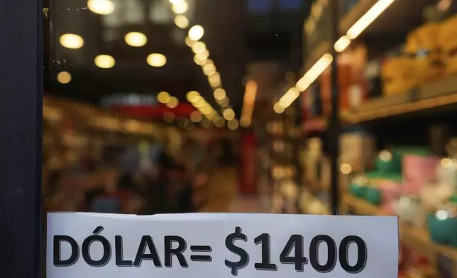 A sign displays the exchange rate between the U.S. dollar and the Argentine peso that is used at a store in Buenos Aires, Argentina, Monday, April 14, 2025. (AP Photo/Natacha Pisarenko)