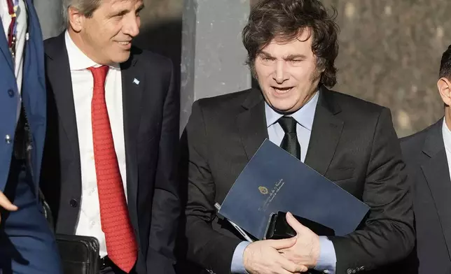 Argentine President Javier Milei, right, and his Economy Minister Luis Caputo enter the Economy Ministry after a meeting with US Treasury Secretary Scott Bessent in Buenos Aires, Argentina, Monday, April 14, 2025. (AP Photo/Natacha Pisarenko)