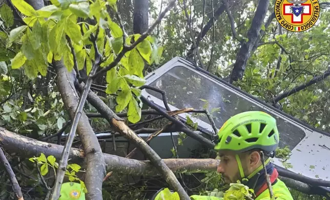 In this photo released by the Italian Alpine and Speleological Rescue Corps on Thursday, April 17, 2025, rescuers reach for the smashed gondola of the Mt. Faito cablecar near Naples in southern Italy.