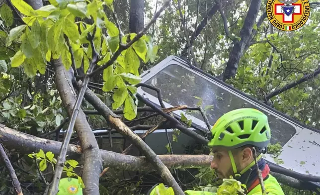 In this photo released by the Italian Alpine and Speleological Rescue Corps on Thursday, April 17, 2025, rescuers reach for the smashed gondola of the Mt. Faito cable car near Naples in southern Italy.