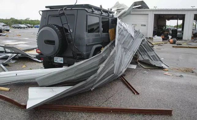 Sheet metal roofing hangs on a damaged car at a local car dealership in Ada, Okla., after severe weather passed the area Sunday, April 20, 2025. (Richard R. Barron/The ADA News via AP)
