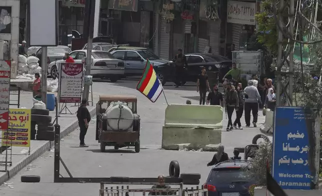 Druze gunmen stand next of their sect religious flag at one of Jaramana suburb entrances checkpoint, after clashes in the area between members of the minority Druze sect and pro-government fighters, in the southern suburb of Jaramana, Damascus, Syria, Wednesday, April 30, 2025. (AP Photo/Omar Sanadiki)