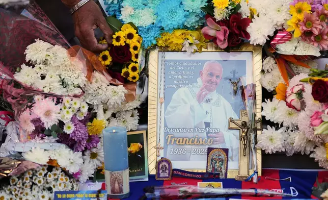 Norberto Rodriguez places flowers near a photo of the late Pope Francis outside the Cathedral in Buenos Aires, Argentina, Tuesday, April 22, 2025. (AP Photo/Natacha Pisarenko)