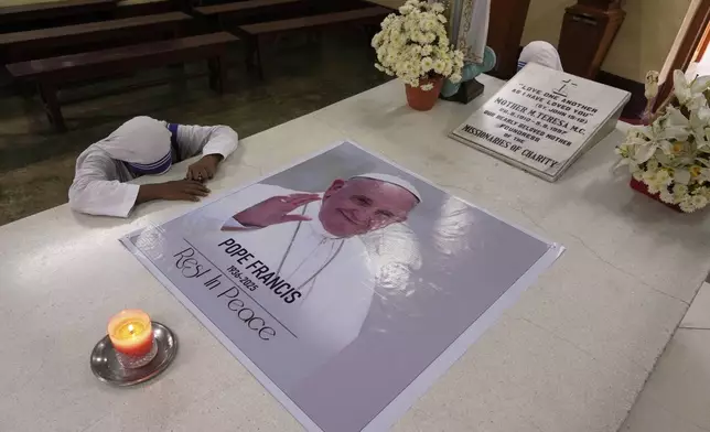 A Catholic nun of the Missionaries of Charity, the order founded by Saint Teresa, prays as a portrait of Pope Francis, placed over the saint's tomb following his death, in Kolkata, India, Tuesday, April 22, 2025. (AP Photo/Bikas Das)