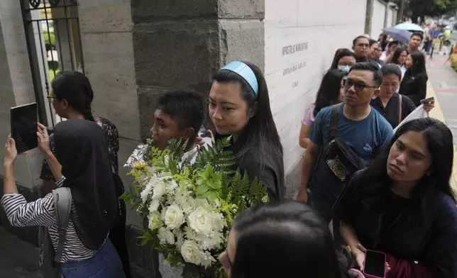 People queue up as they wait for their turn to be allowed in to the Apostolic Nunciature to offer their condolences, in Jakarta, Indonesia, Tuesday, April 22, 2025. (AP Photo/Dita Alangkara)