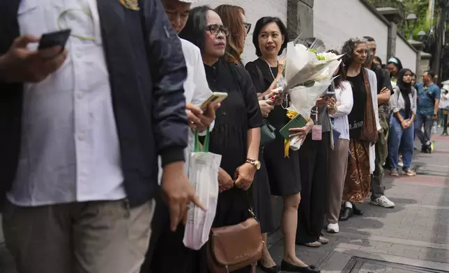 People wait in line for their turn to be allowed in to the Apostolic Nunciature to offer their condolences, in Jakarta, Indonesia, Tuesday, April 22, 2025. (AP Photo/Dita Alangkara)