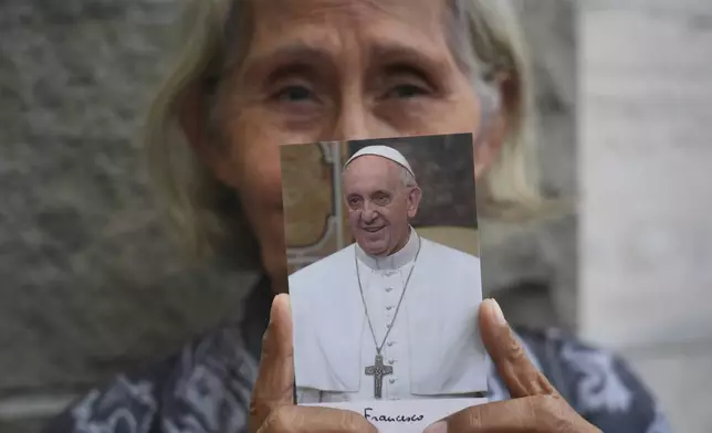 A woman holds a portrait of the late Pope Francis at the Apostolic Nunciature in Jakarta, Indonesia, Tuesday, April 22, 2025. (AP Photo/Tatan Syuflana)