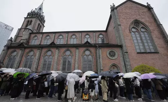 People wait in line to enter Myeongdong Cathedral to pay tribute for the late Pope Francis in Seoul, South Korea, Tuesday, April 22, 2025. (AP Photo/Ahn Young-joon)