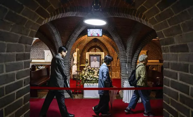 People pay their respects in front of a portrait of late Pope Francis displayed inside Myeongdong Cathedral in Seoul Tuesday, April 22, 2025. (Anthony Wallace/Pool Photo via AP)