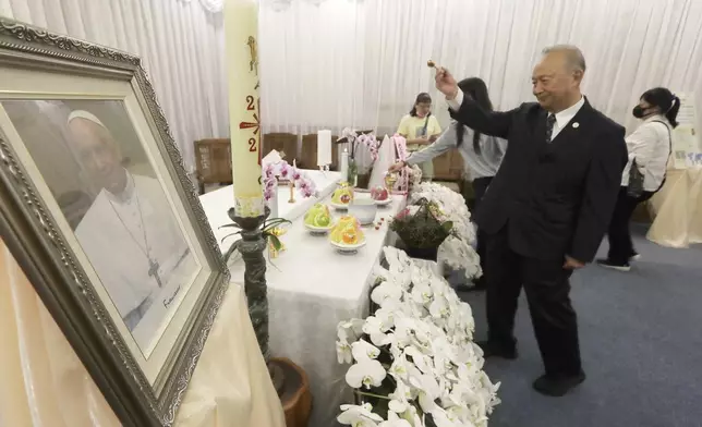 Taiwanese people pay their respects in front of a portrait of Pope Francis in Taipei, Taiwan, Tuesday, April 22, 2025. (AP Photo/Chiang Ying-ying)