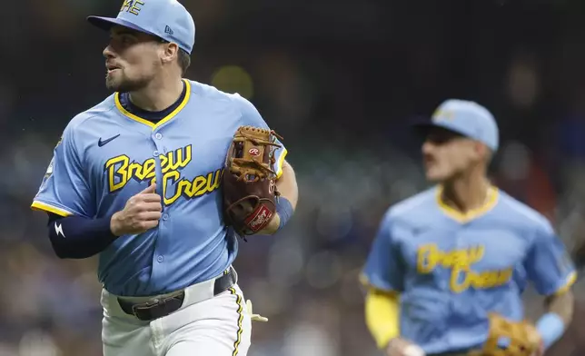 Milwaukee Brewers' Caleb Durbin, left, runs off the field in the first inning of a baseball game against the Athletics, Friday, April 18, 2025, in Milwaukee. (AP Photo/Jeffrey Phelps)