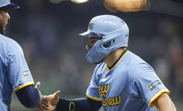 Milwaukee Brewers' Caleb Durbin, right, reacts after his first major league hit with first base coach Julio Borbon against the Athletics in the third inning of a baseball game Friday, April 18, 2025, in Milwaukee. (AP Photo/Jeffrey Phelps)