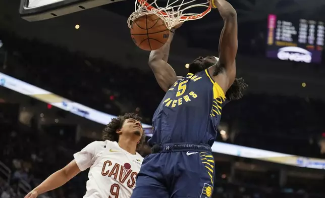 Indiana Pacers forward Jarace Walker (5) dunks next to Cleveland Cavaliers guard Craig Porter Jr. (9) in the first half of an NBA basketball game Sunday, April 13, 2025, in Cleveland. (AP Photo/Sue Ogrocki)