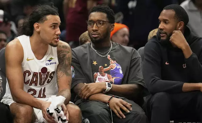 Cleveland Cavaliers forward Jaylon Tyson, left, talks with Donovan Mitchell, center, and Evan Mobley, right, who did not dress for the game, in the first half of an NBA basketball game against the Indiana Pacers Sunday, April 13, 2025, in Cleveland. (AP Photo/Sue Ogrocki)