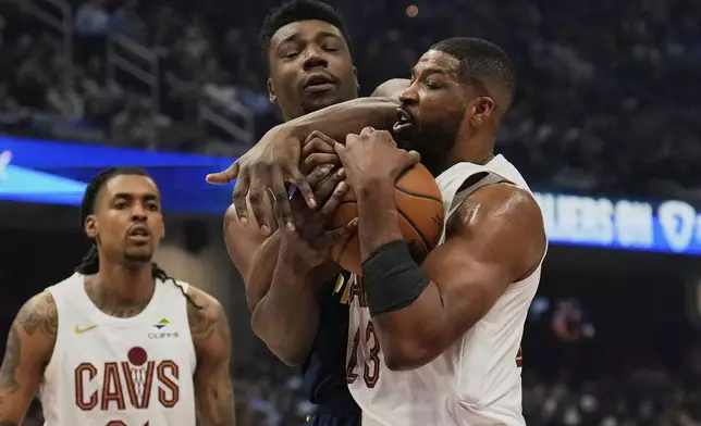 Indiana Pacers center Thomas Bryant, center, and Cleveland Cavaliers center Tristan Thompson (13) fight for control of the ball in the first half of an NBA basketball game Sunday, April 13, 2025, in Cleveland. (AP Photo/Sue Ogrocki)