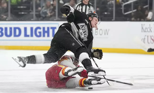 Los Angeles Kings center Samuel Helenius, top, trips over Calgary Flames left wing Aydar Suniev during the first period of an NHL hockey game Thursday, April 17, 2025, in Los Angeles. (AP Photo/Mark J. Terrill)