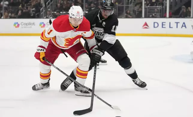 Calgary Flames center Mikael Backlund, left, and Los Angeles Kings center Anze Kopitar battle for the puck during the first period of an NHL hockey game Thursday, April 17, 2025, in Los Angeles. (AP Photo/Mark J. Terrill)
