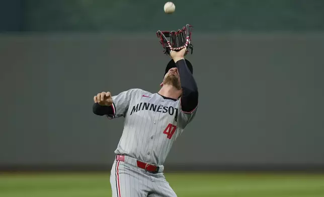 Minnesota Twins second baseman Edouard Julien catches a fly ball for the out on Kansas City Royals' Hunter Renfroe during the third inning of a baseball game, Wednesday, April 9, 2025, in Kansas City, Mo. (AP Photo/Charlie Riedel)