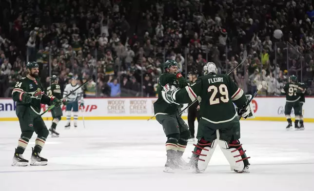 Minnesota Wild defenseman Brock Faber (7), center, and goaltender Marc-Andre Fleury (29) celebrate after the overtime win against the San Jose Sharks of an NHL hockey game, Wednesday, April 9, 2025, in St. Paul, Minn. (AP Photo/Abbie Parr)