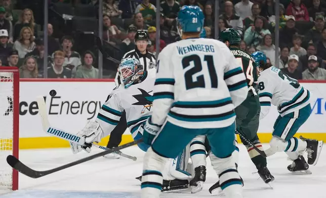 San Jose Sharks goaltender Alexandar Georgiev (40), back, left, defends against a shot during the first period of an NHL hockey game against the Minnesota Wild, Wednesday, April 9, 2025, in St. Paul, Minn. (AP Photo/Abbie Parr)