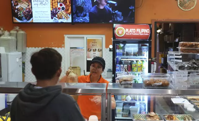 April Palma, center, helps a customer at Plato Filipino restaurant in Vancouver, British Columbia, Monday, April 28, 2025. (AP Photo/Lindsey Wasson)