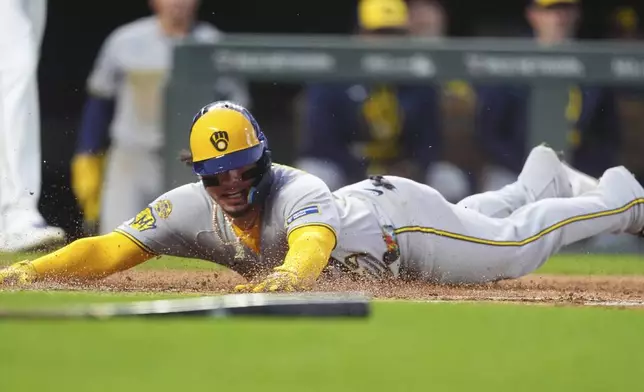 Milwaukee Brewers' William Contreras slides safely into home plate to score on a single hit by Sal Frelick in the third inning of a baseball game against the Colorado Rockies Tuesday, April 8, 2025, in Denver. (AP Photo/David Zalubowski)