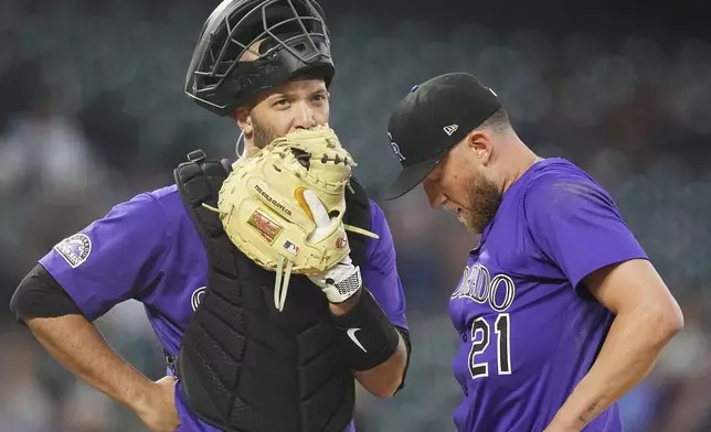 Colorado Rockies catcher Jacob Stallings, left, confers with starting pitcher Kyle Freeland after he gave up an RBI single to Milwaukee Brewers' William Contreras in the third inning of a baseball game Tuesday, April 8, 2025, in Denver. (AP Photo/David Zalubowski)