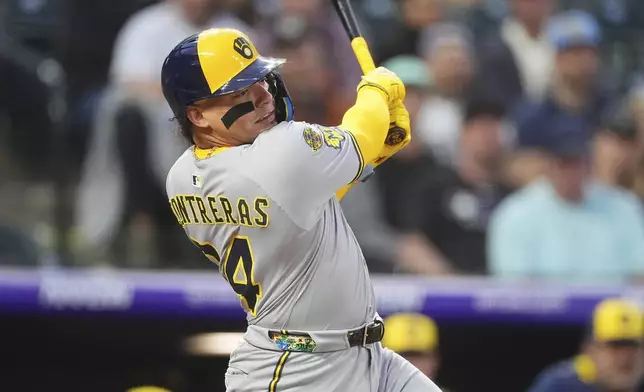 Milwaukee Brewers' William Contreras follows the flight of his RBI single against Colorado Rockies starting pitcher Kyle Freeland in the third inning of a baseball game Tuesday, April 8, 2025, in Denver. (AP Photo/David Zalubowski)