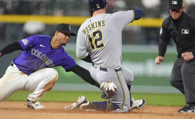 Colorado Rockies shortstop Ezequiel Tovar, left, tags out Milwaukee Brewers' Rhys Hoskins as he tries to steal second base in the seventh inning of a baseball game Tuesday, April 8, 2025, in Denver. (AP Photo/David Zalubowski)