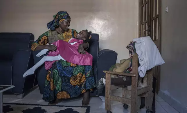 Fatoumata Sané holds her daughter Aissata, 8, who suffers from a rare genetic disease, at their home in Dakar, Senegal, Saturday, Jan. 11, 2025. (AP Photo/Annika Hammerschlag)