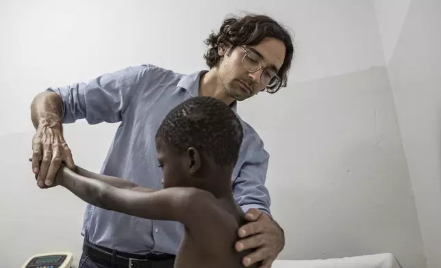 Rare disease researcher Pedro Rodriguez, left, examines Ibrahima Ndiaye, 8, in Dakar, Senegal, Friday, Jan. 10, 2025. (AP Photo/Annika Hammerschlag)