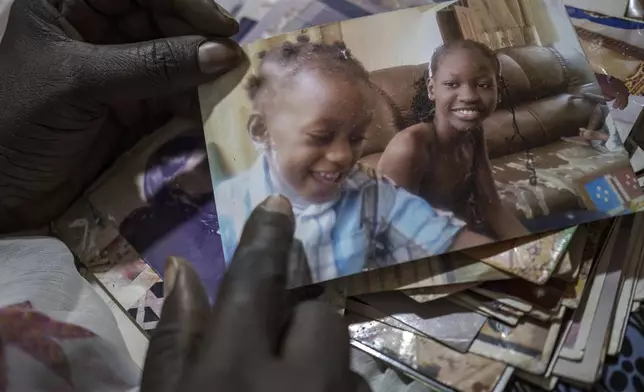 Ndeye Lam looks at photos of her deceased daughter Mariama who died at age 13 of a rare genetic disease, in Dakar, Senegal, Saturday, Jan. 11, 2025. (AP Photo/Annika Hammerschlag)