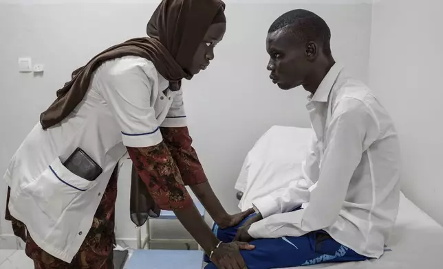 Neurology student Henriette Dieng examines Abdou Diop, a patient with genetic neuropathy at Pedro Rodriguez's clinic in Dakar, Senegal, Friday, Jan. 10, 2025. (AP Photo/Annika Hammerschlag)