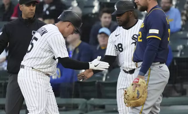 Chicago White Sox's Andrew Vaughn, left, celebrates with first base coach Jason Bourgeois after hitting a single during the first inning of a baseball game against the Milwaukee Brewers in Chicago, Tuesday, April 29, 2025. (AP Photo/Nam Y. Huh)