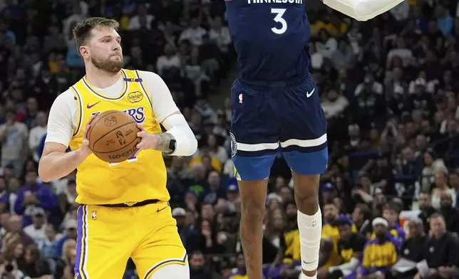 Los Angeles Lakers guard Luka Doncic (77) looks to pass as Minnesota Timberwolves forward Jaden McDaniels (3) defends during the second half of Game 3 of an NBA basketball first-round playoff series, Friday, April 25, 2025, in Minneapolis. (AP Photo/Abbie Parr)