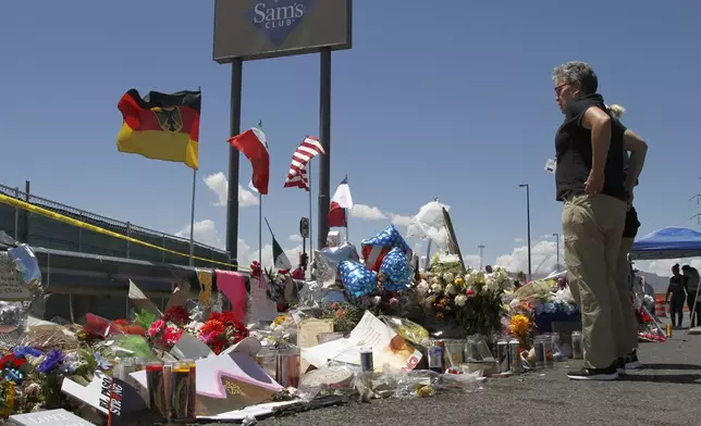 FILE - In this Aug. 12, 2019 photo, mourners visit the makeshift memorial near the Walmart in El Paso, Texas. (AP Photo/Cedar Attanasio, File)
