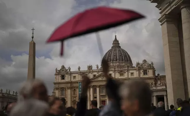 People wait in line under the rain to enter St.Peter's Basilica to view Pope Francis lying in state, at the Vatican, Thursday, April 24, 2025. (AP Photo/Francisco Seco)