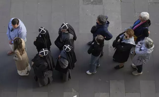 A group of four nuns, center left, wait in line with other people to view Pope Francis lying in state inside St. Peter's Basilica, at the Vatican, Thursday, April 24, 2025. (AP Photo/Markus Schreiber)