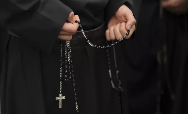 A faithful holds a rosary while waiting in line to enter St.Peter's Basilica to view Pope Francis lying in state, at the Vatican, Thursday, April 24, 2025. (AP Photo/Francisco Seco)