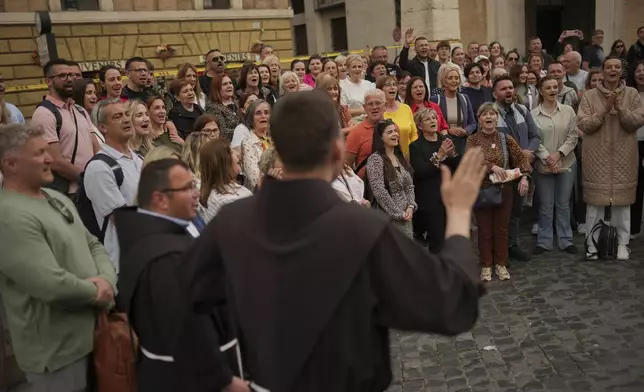 A chorus of people sing religious songs near St. Peter's Square to enter the Vatican, Wednesday, April 23, 2025, as the body of the late Pope Francis will lie in state inside St. Peter's Basilica for three days. (AP Photo/Francisco Seco)