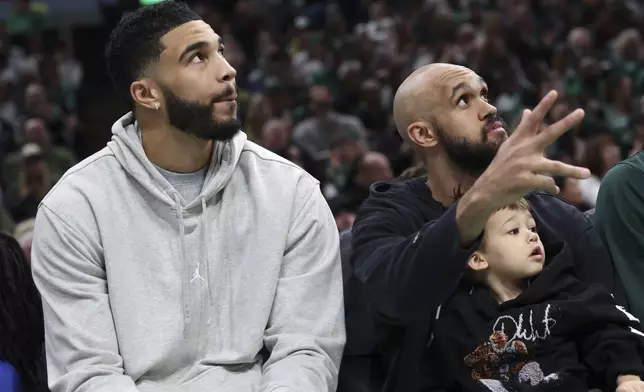 Boston Celtics' Jayson Tatum, left, and Derrick White watch from the bench during the first half of an NBA basketball game against the Charlotte Hornets Sunday, April 13, 2025, in Boston. (AP Photo/Michael Dwyer)