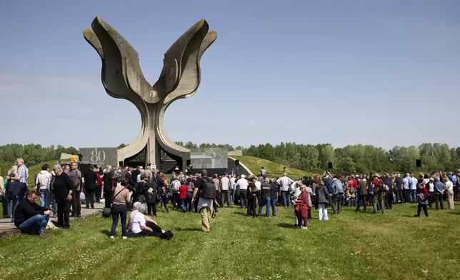 People gather around the monument commemorating victims of a World War II concentration camp, where tens of thousands of people perished in the hands of the pro-Nazi puppet regime at the time, in Jasenovac, Croatia, Tuesday, April 22, 2025. (AP Photo)