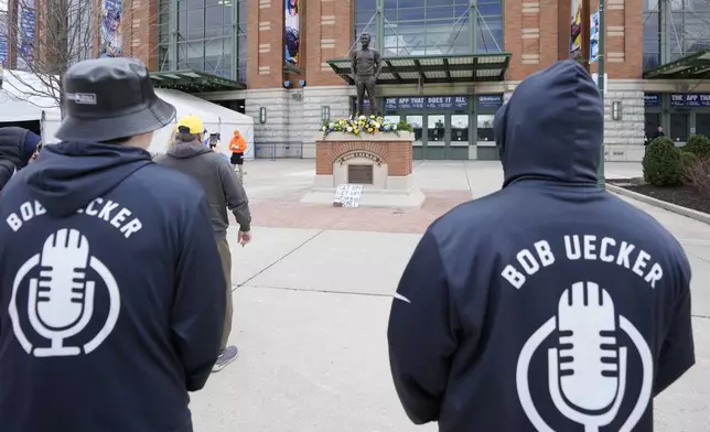 Sean Woods, left, and David Woods observe the memorial at the Bob Uecker statue in front of American Family Field prior to a baseball game between the Milwaukee Brewers and the Kansas City Royals on Opening Day Monday, March 31, 2025, in Milwaukee. (AP Photo/Kayla Wolf)
