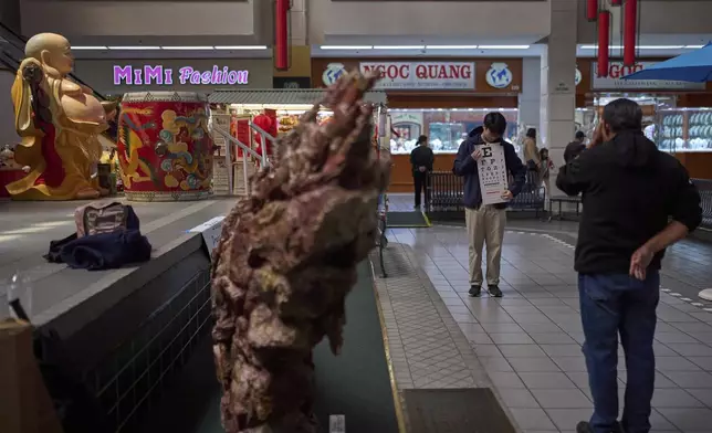 Erik Nguyen, a volunteer and UCLA student, holds a vision chart for a participant during a Vietnamese Community Health Project event at Asian Garden Mall in the Little Saigon neighborhood of Westminster, Calif., Saturday, April 26, 2025. (AP Photo/Jae C. Hong)
