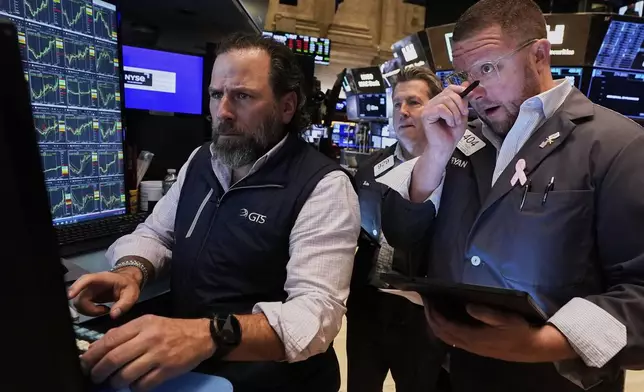 Specialist Michel Pistillo, left, works with traders James Matthews, center, and Ryan Falvey on the floor of the New York Stock Exchange, Wednesday, April 23, 2025. (AP Photo/Richard Drew)